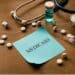 Sticky note that says "Medicaid" surrounded by pills and a syringe on a wooden table