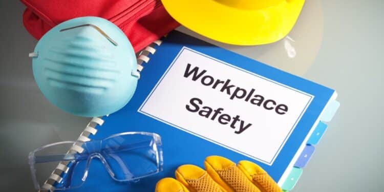 Book with the title "workplace safety" with gloves, a hard hat, and a mask surrounding it