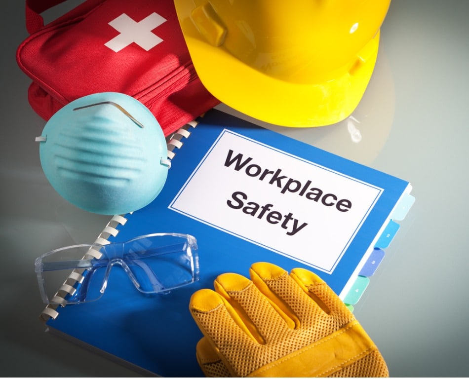 Book with the title "workplace safety" with gloves, a hard hat, and a mask surrounding it