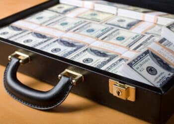 Attache filled with money sitting on a wooden table