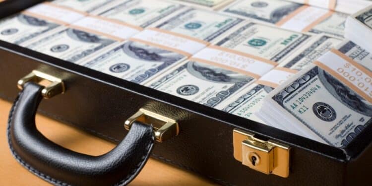 Attache filled with money sitting on a wooden table