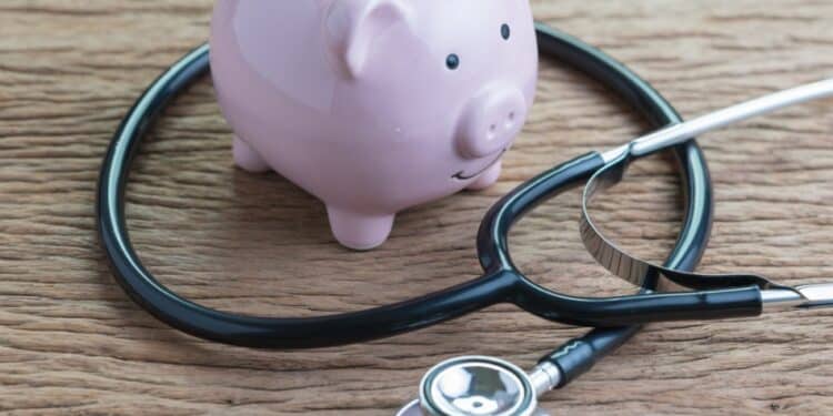Pink piggy bank on a wooden table with a stethoscope