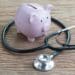 Pink piggy bank on a wooden table with a stethoscope