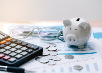 Piggy bank, calculator, and glasses on financial documents