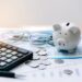 Piggy bank, calculator, and glasses on financial documents