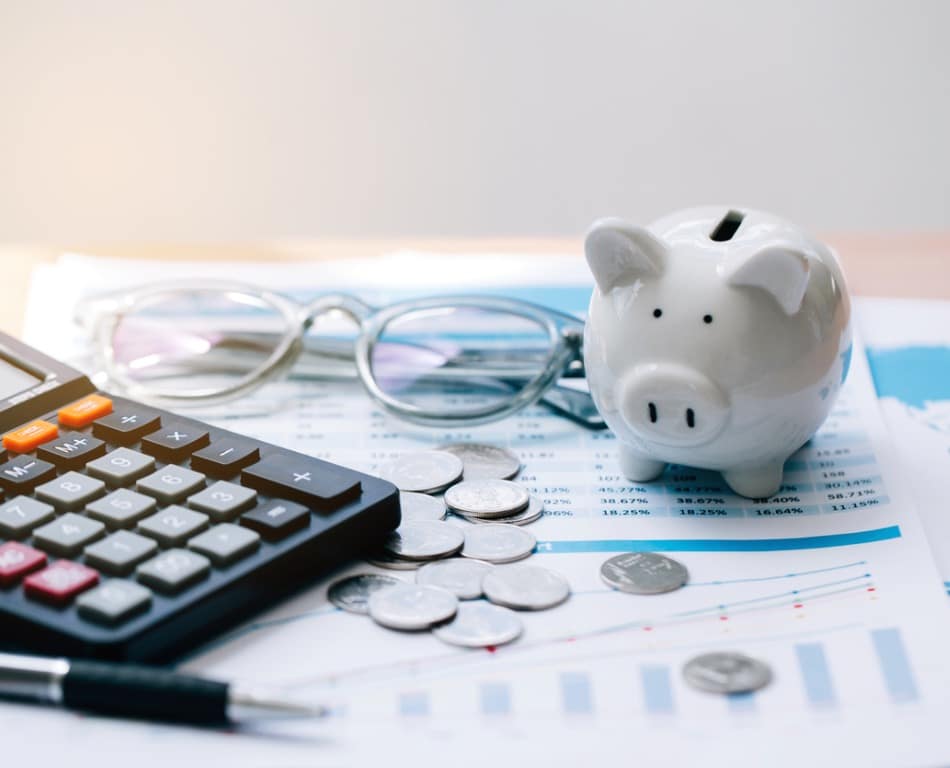 Piggy bank, calculator, and glasses on financial documents